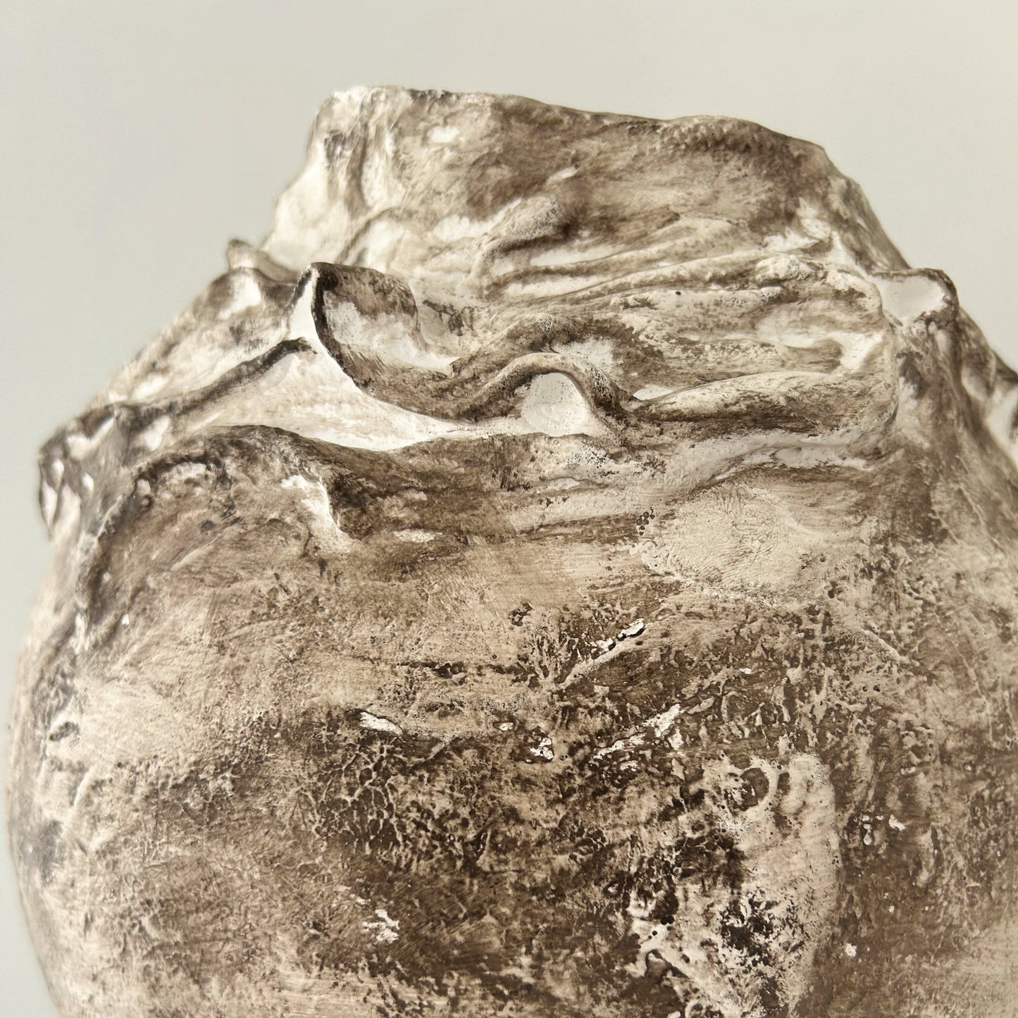 Close-up detail of abstract rim and rich earthy surface of sculptural vase.
