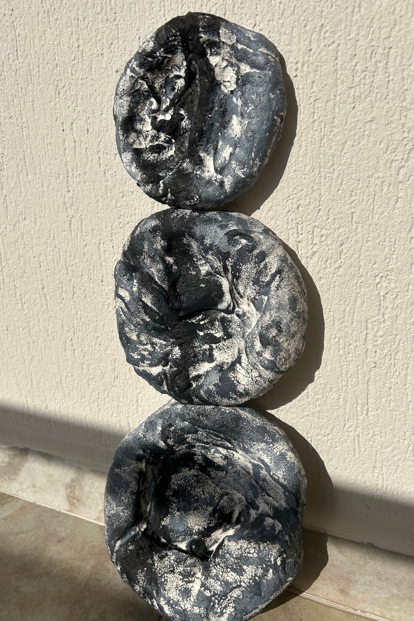Set of three handmade round plaster wall sculptures with dark grey textured finish