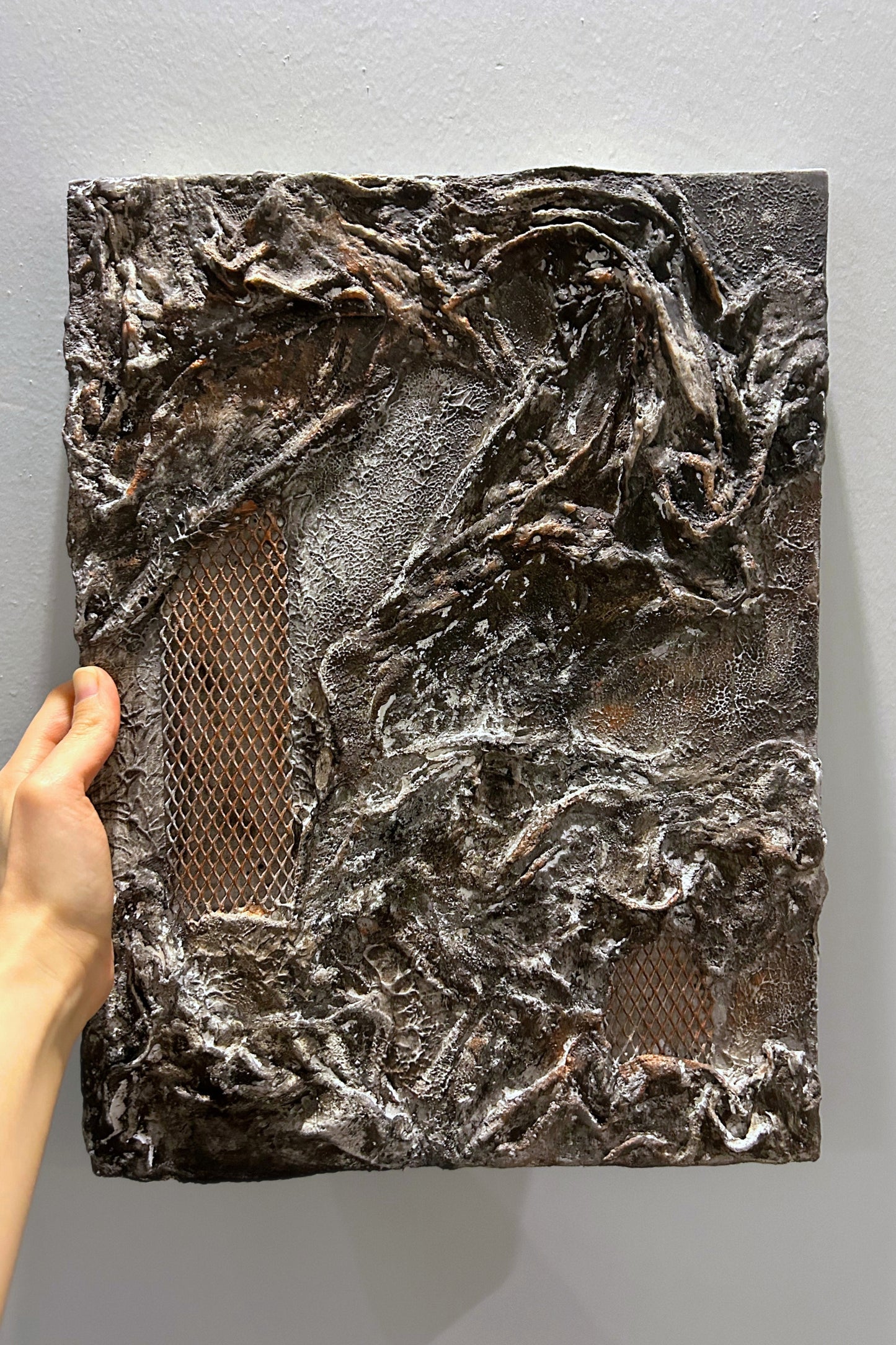 Wall art panel held in hand under warm indoor lighting, showing natural surface variation.