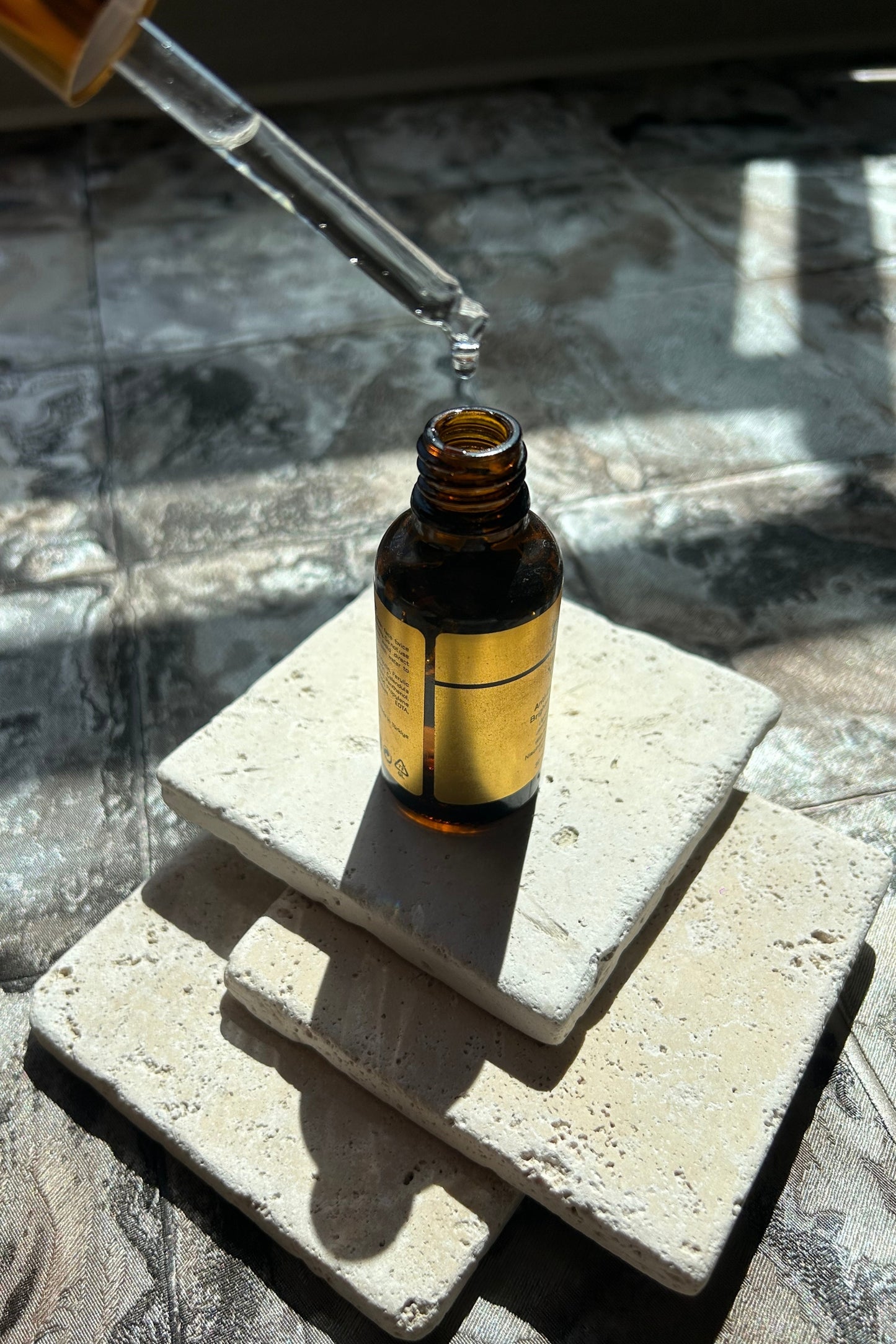 Natural travertine styling stone stacked with amber bottle for product photography