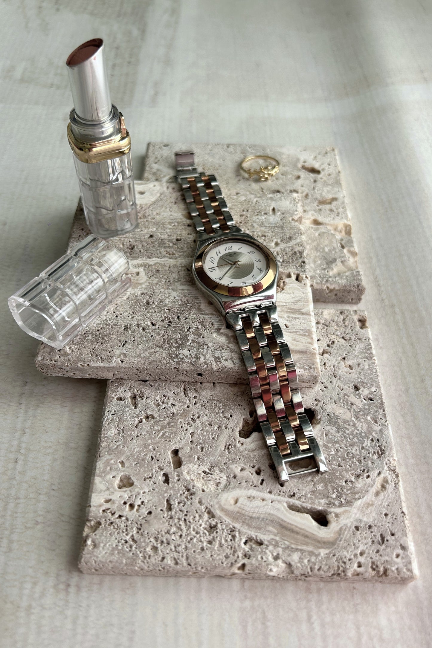 Flatlay of travertine stone blocks styled with jewelry on a white background