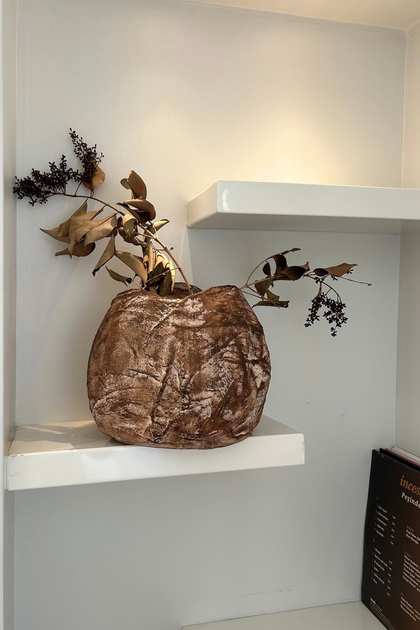 Sculptural handmade vase styled on a neutral-toned mantel with calming decor elements.