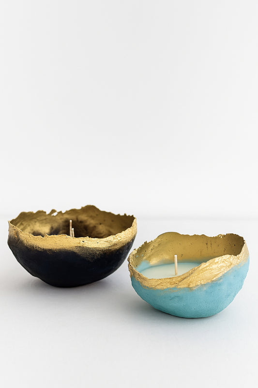 Two handmade paper mache candle bowls in black and turquoise with gold-painted textured edges, styled on a white minimalist background.