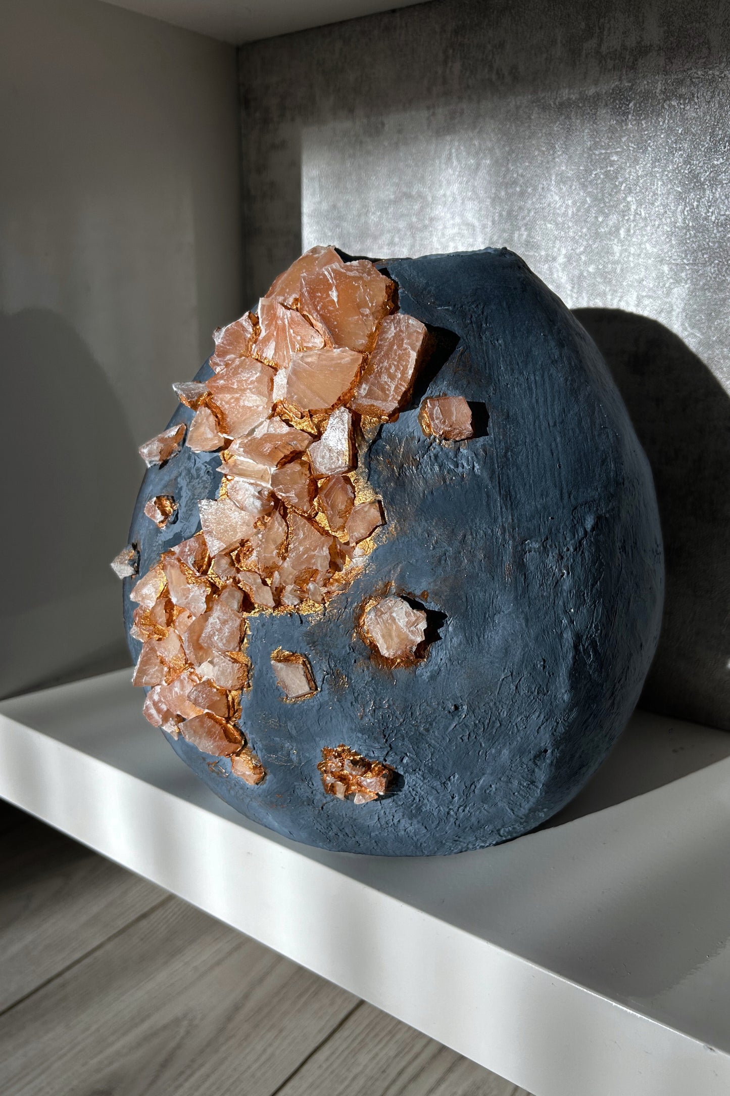 Wabi-sabi vase in sunlight highlighting dark blue tones and stones