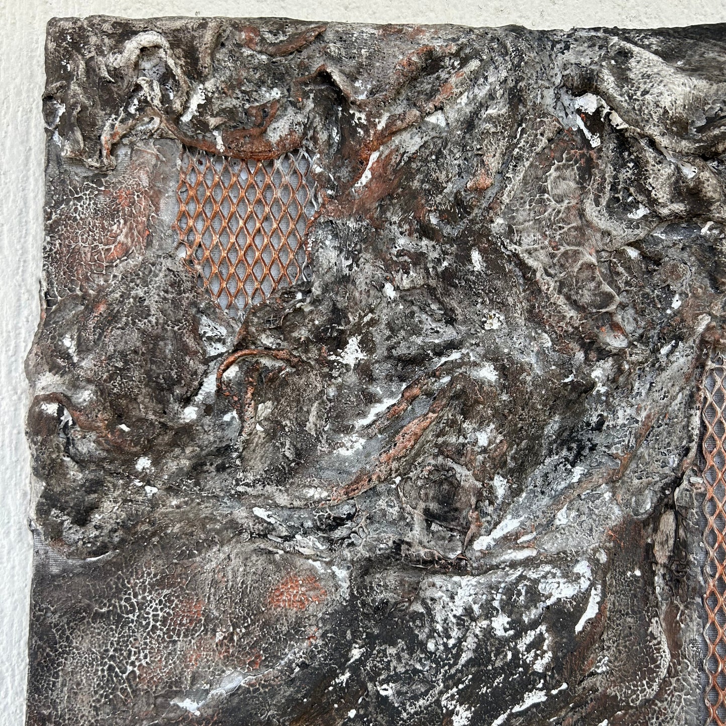 Top left detail of textured plaster with earthy tones and metallic highlights.