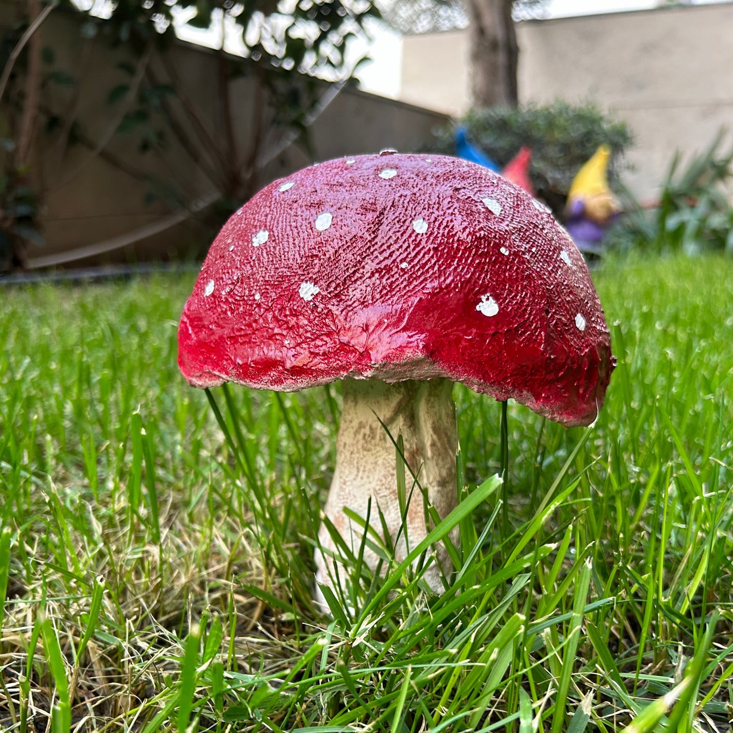 Paper mache mushroom sculpture placed on fresh green grass, side angle view