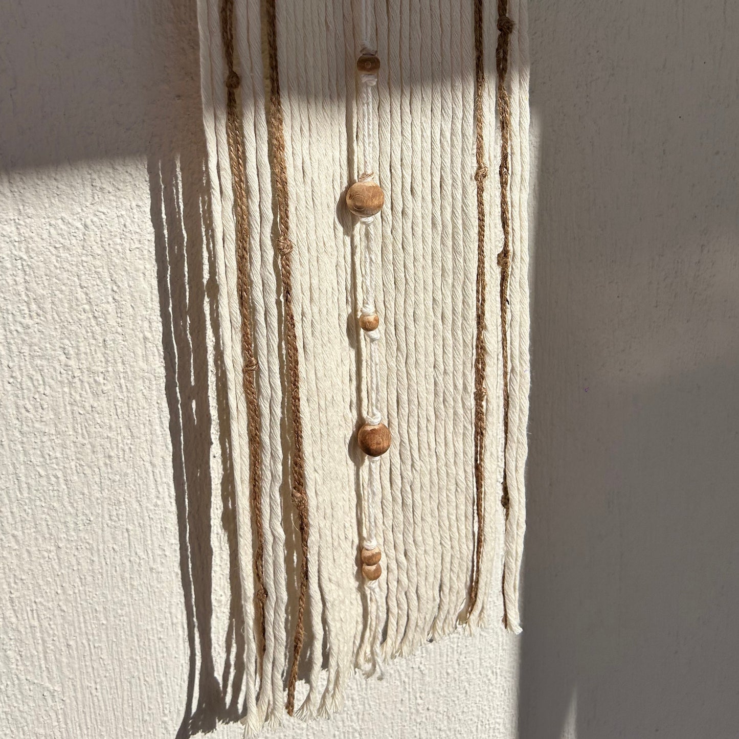 Close-up of wooden beads aligned vertically on neutral yarn strands.