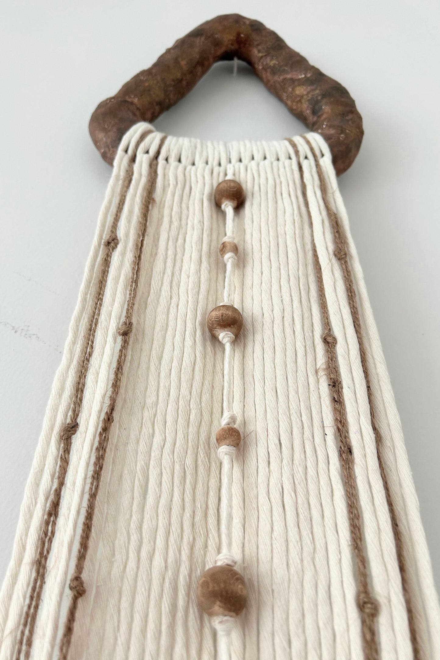 Wabi sabi-inspired neutral yarn wall decor laid flat against a cream backdrop.