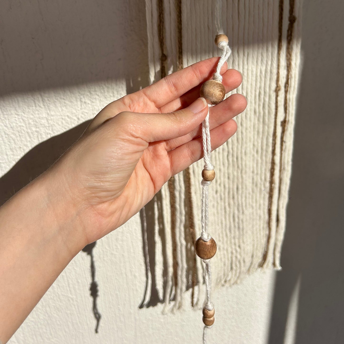 A hand interacting with the yarn strands, emphasizing soft and organic texture.