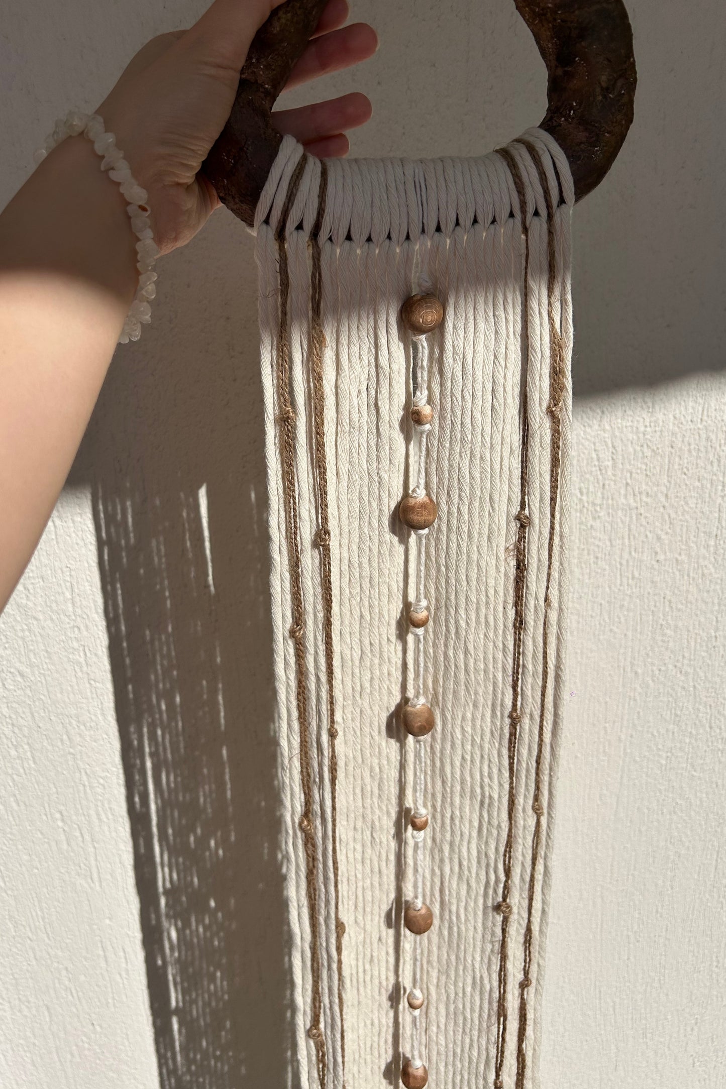 Cropped vertical shot highlighting texture of handmade yarn and jute wall hanging.
