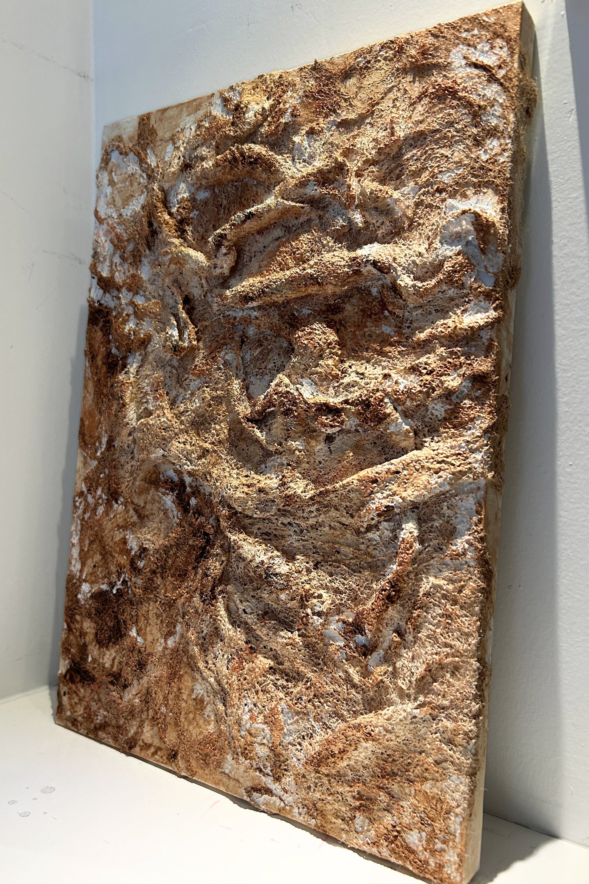 Angled view of handmade wall decor piece revealing copper highlights and texture.