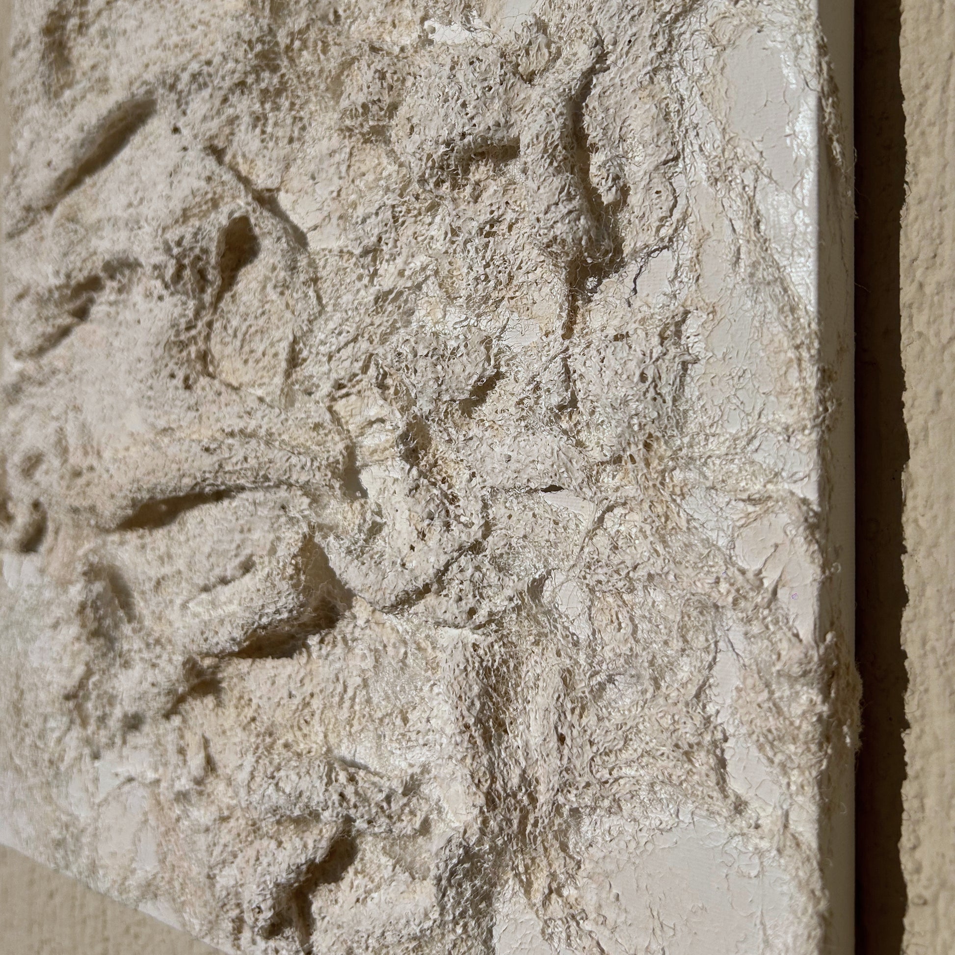 Side angle showing the depth and movement in the handmade white textured canvas wall piece.