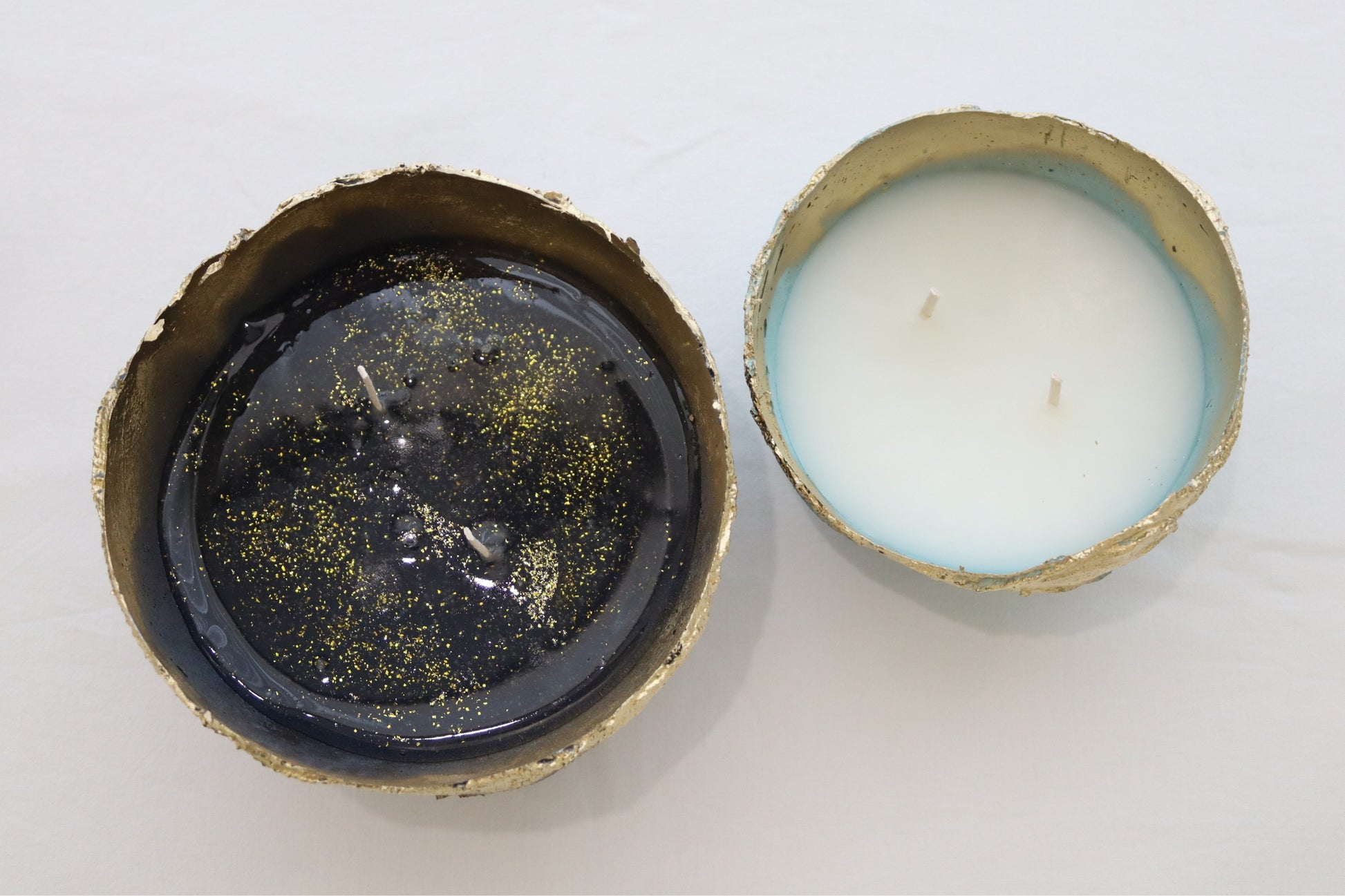Top view of two handmade candle bowls in blue and navy with contrasting wax tones.