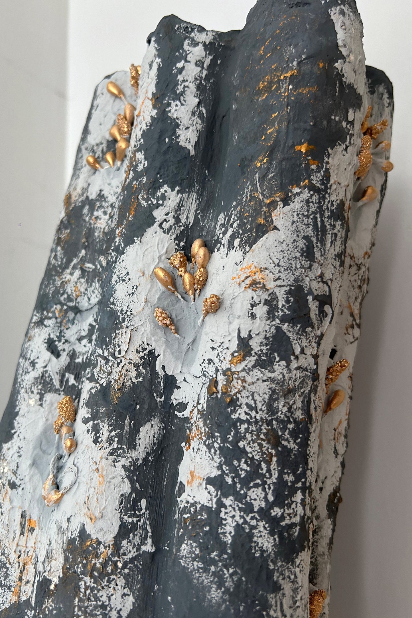 Close-up of handmade vase showing sculptural texture and antique gold beads in wabi sabi style.