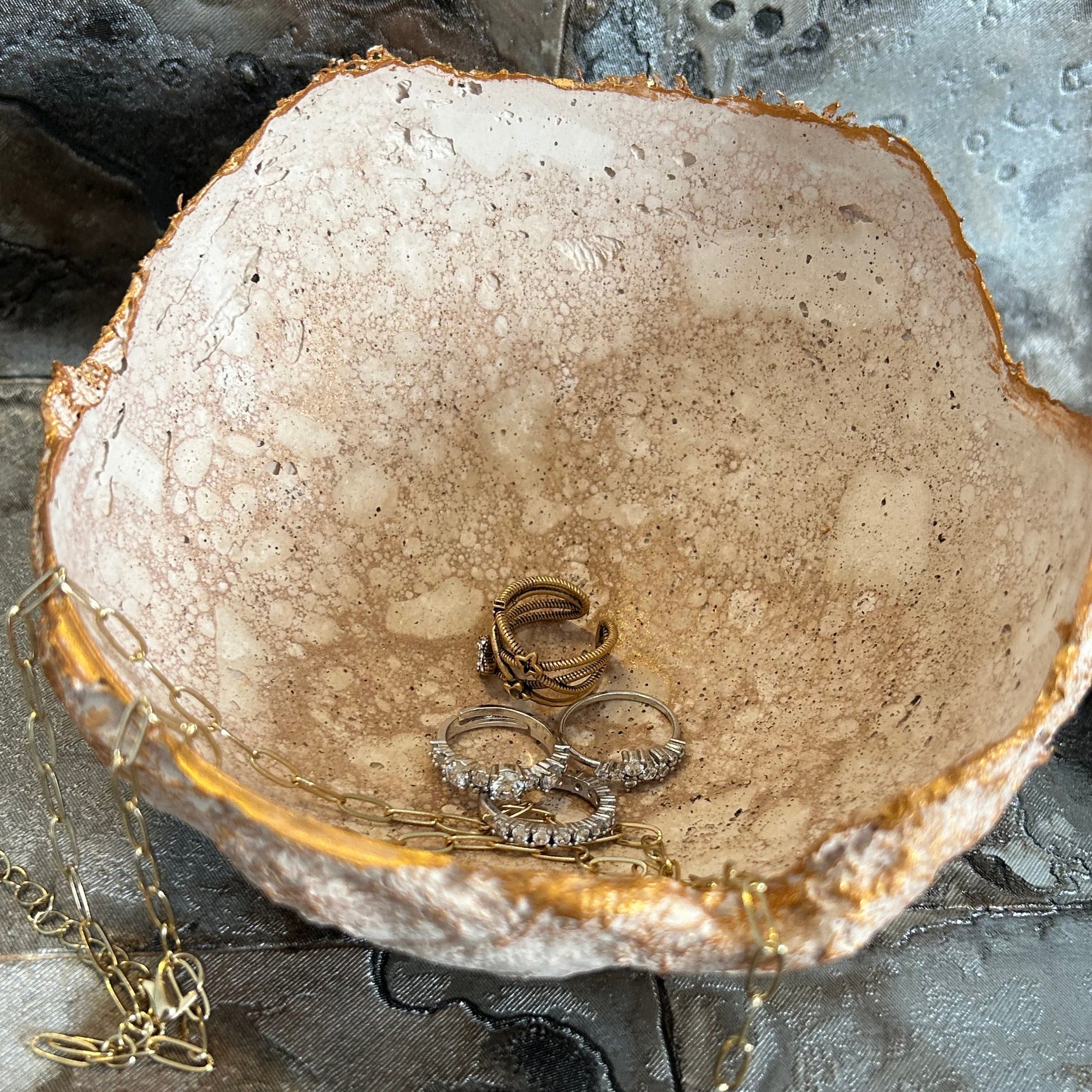 Interior view of the decorative bowl filled with rings and styled on marbled background.