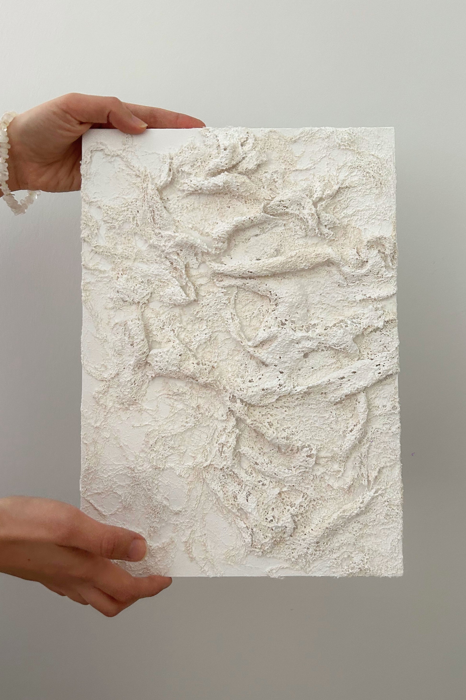 Full-size view of handmade canvas wall art held between two hands, showing scale and detail.