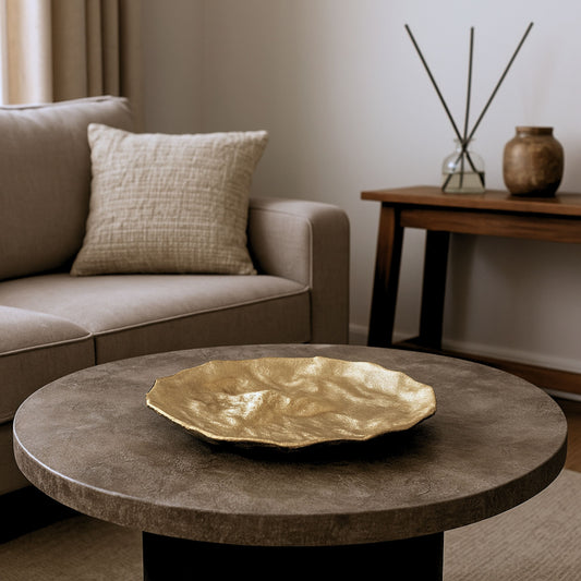  Sculptural handmade gold bowl displayed on a coffee table in a modern neutral-toned living room