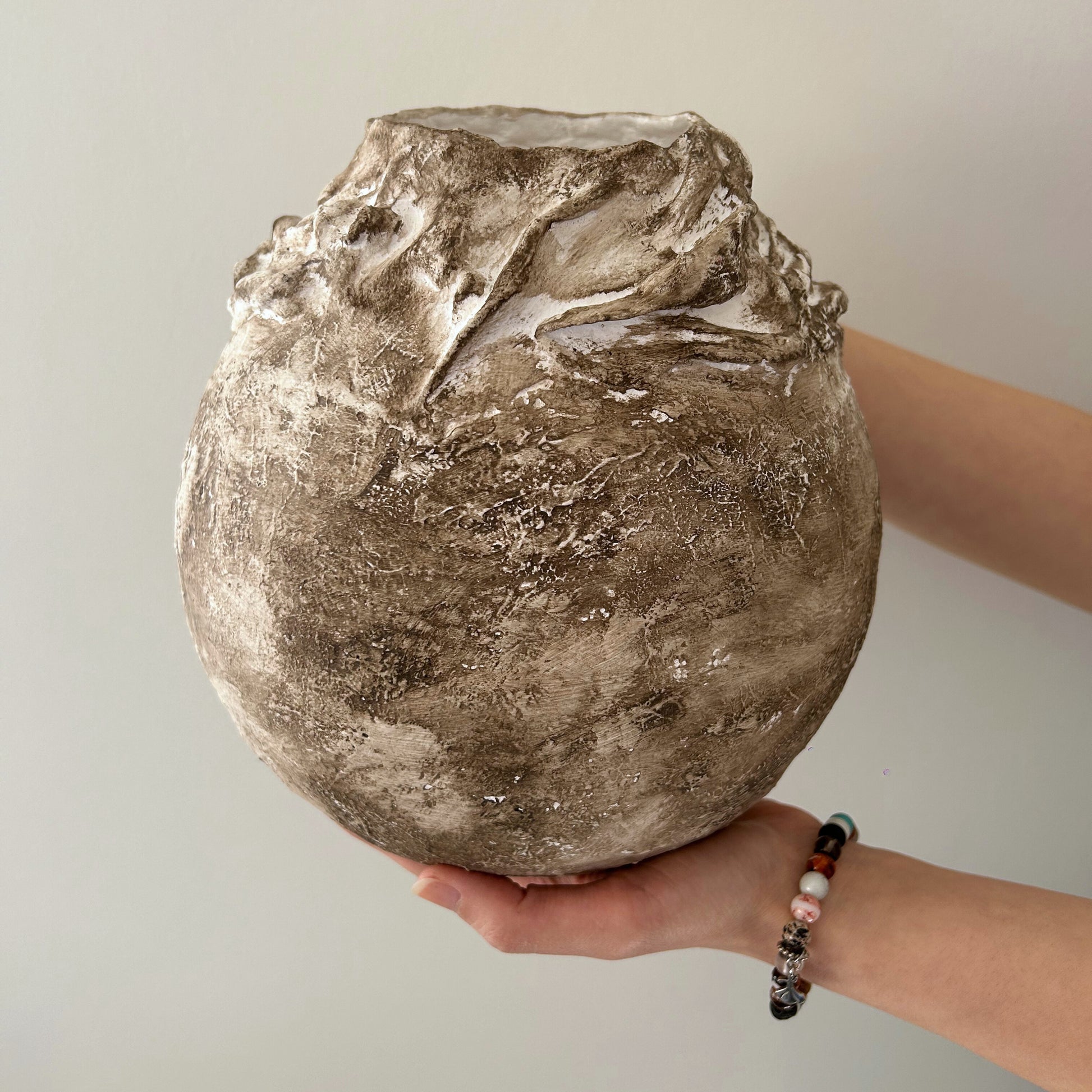 Wabi-sabi handmade vase placed on a round wooden coffee table in modern living room.
