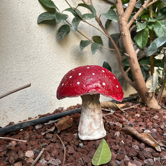 Handmade red mushroom decor styled on a garden bed with natural surroundings