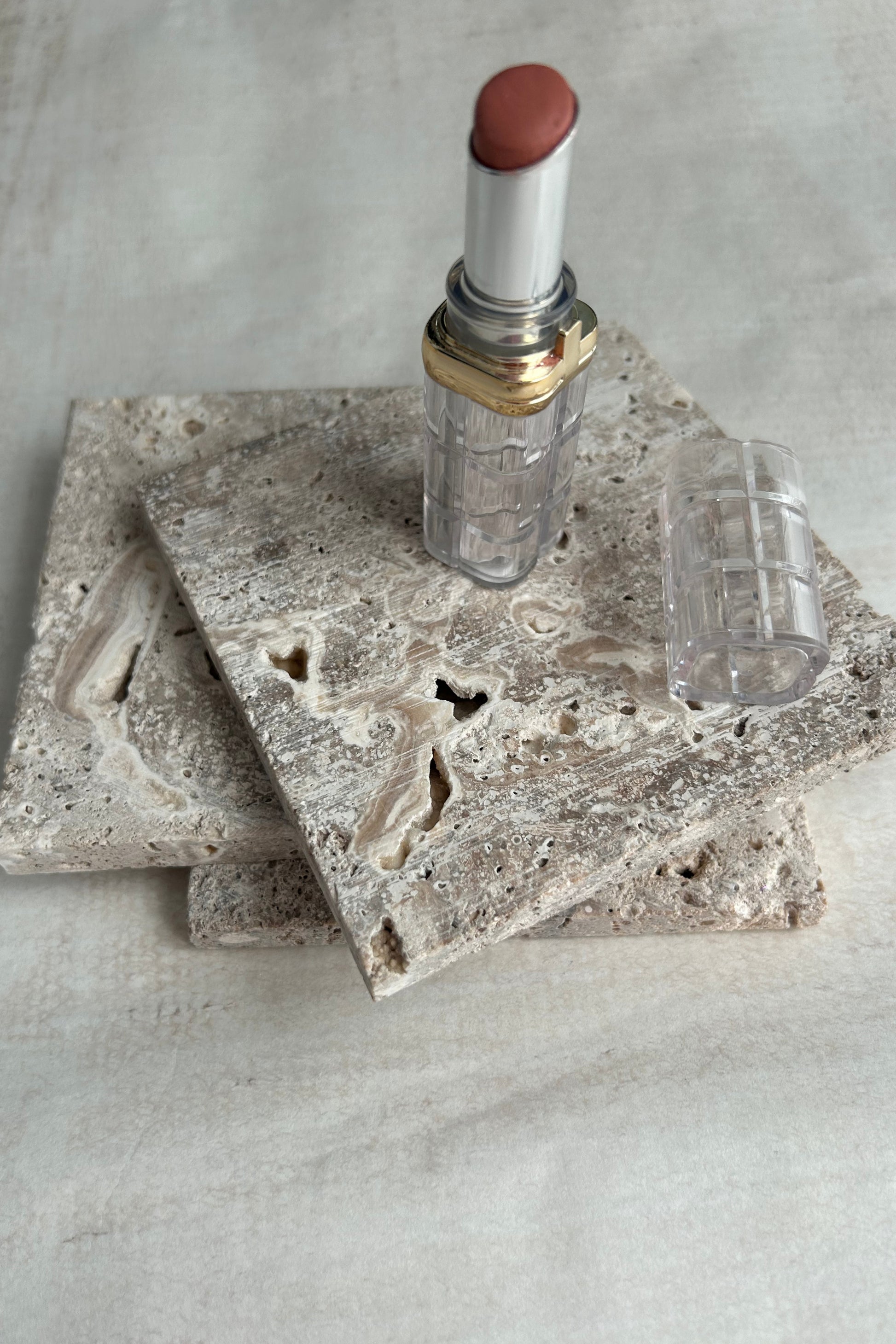 Lipstick and beige travertine blocks used as elegant styling surface