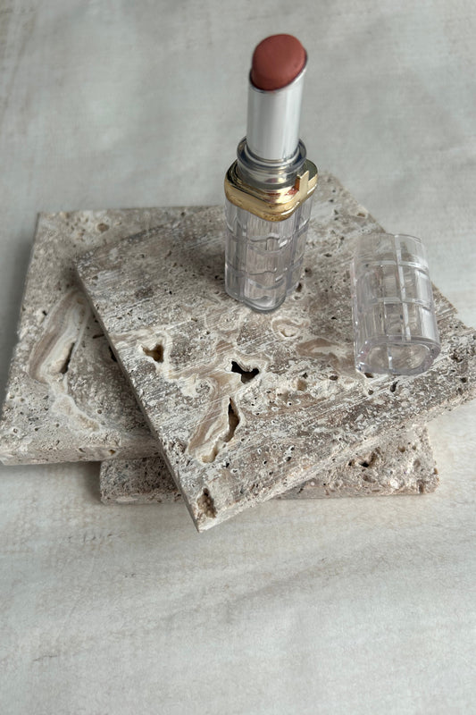 Lipstick and beige travertine blocks used as elegant styling surface