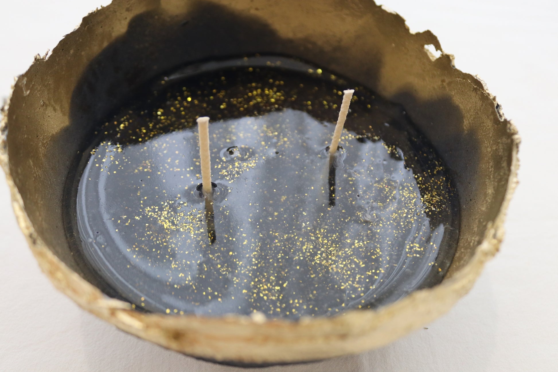 Close-up of navy paper mache bowl filled with black jelly wax and dual wicks.