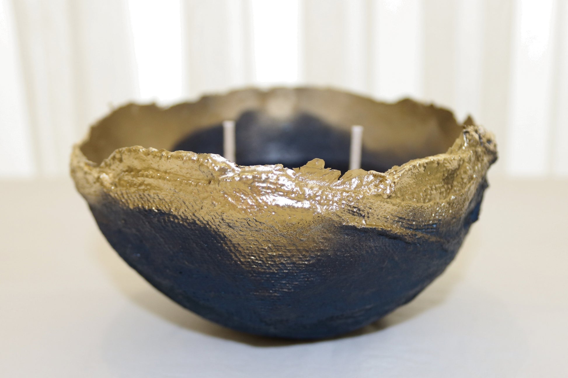  Side view of navy handmade bowl with shimmering gold interior and soft lighting.