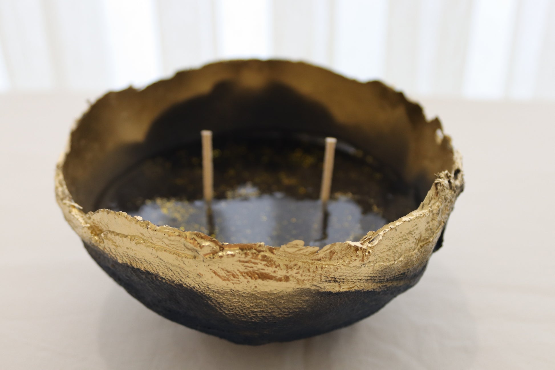 Top view of navy candle bowl with glossy jelly wax and floating golden specks.