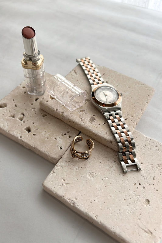 Jewelry display using natural stone prop with watch and rings on beige tray
