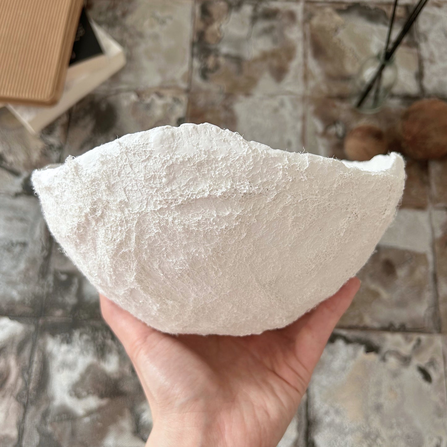 Hand holding a handmade white wabi sabi bowl to highlight size and sculptural form