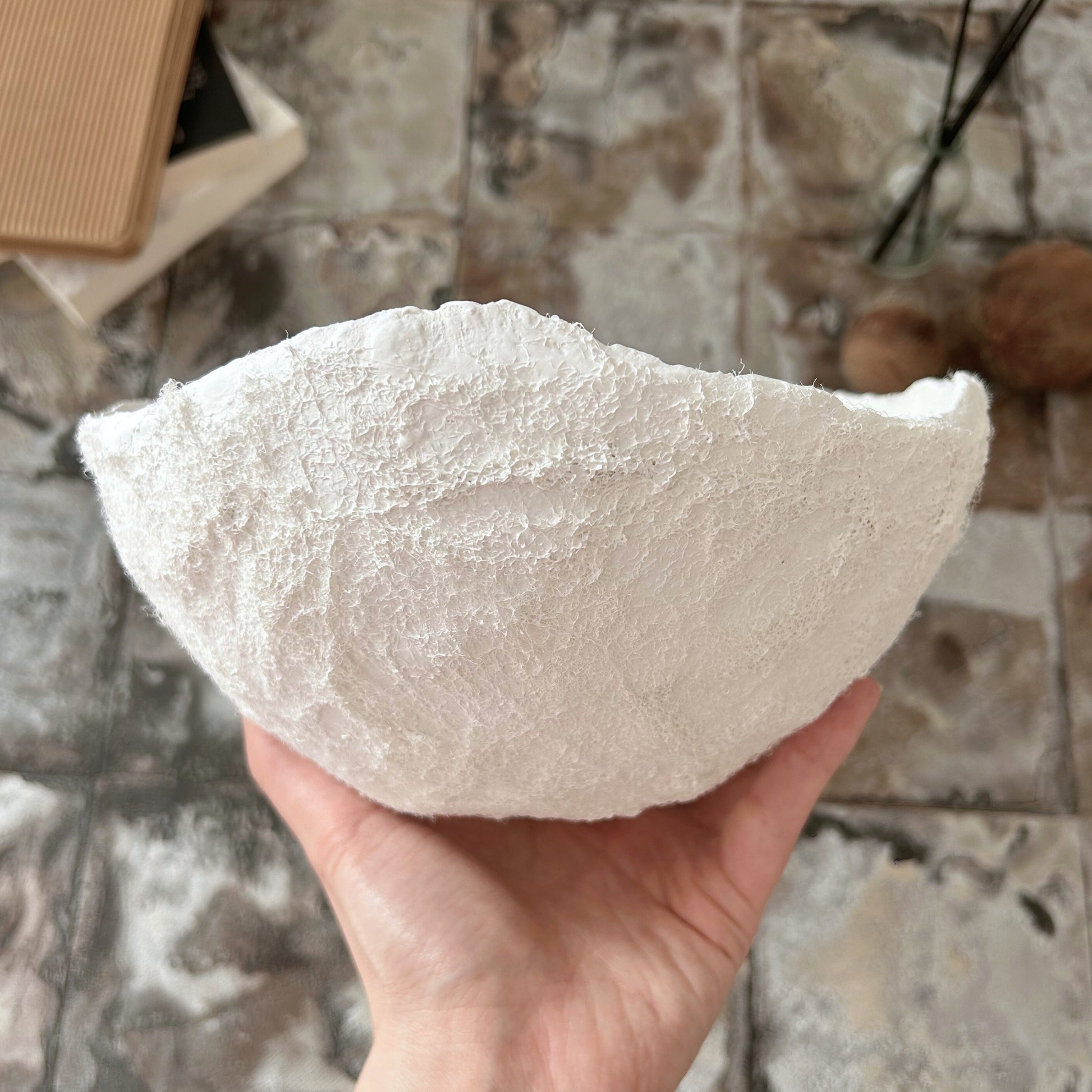 Hand holding a handmade white wabi sabi bowl to highlight size and sculptural form
