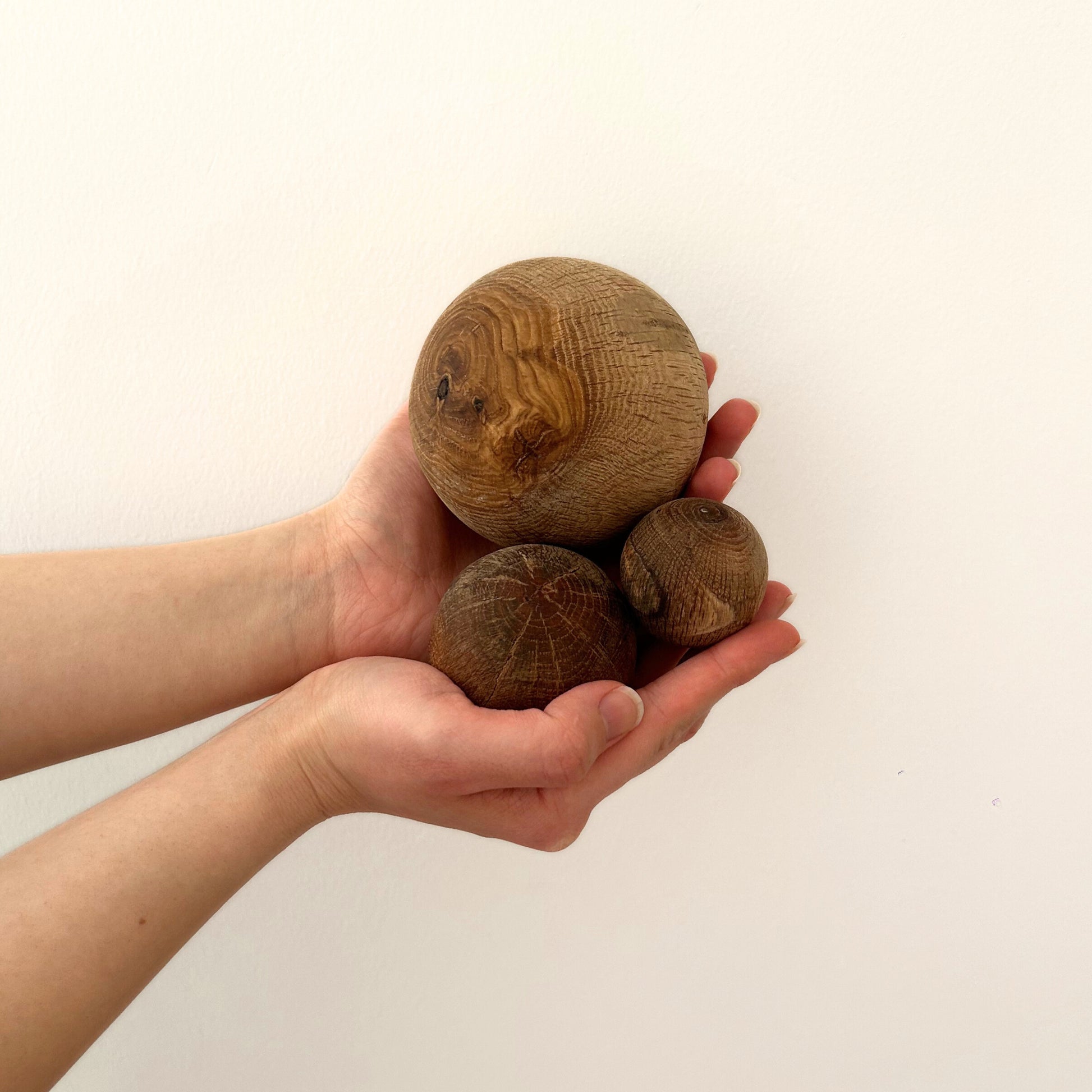 A single small wood decor ball shown in hand for scale and natural texture detail.