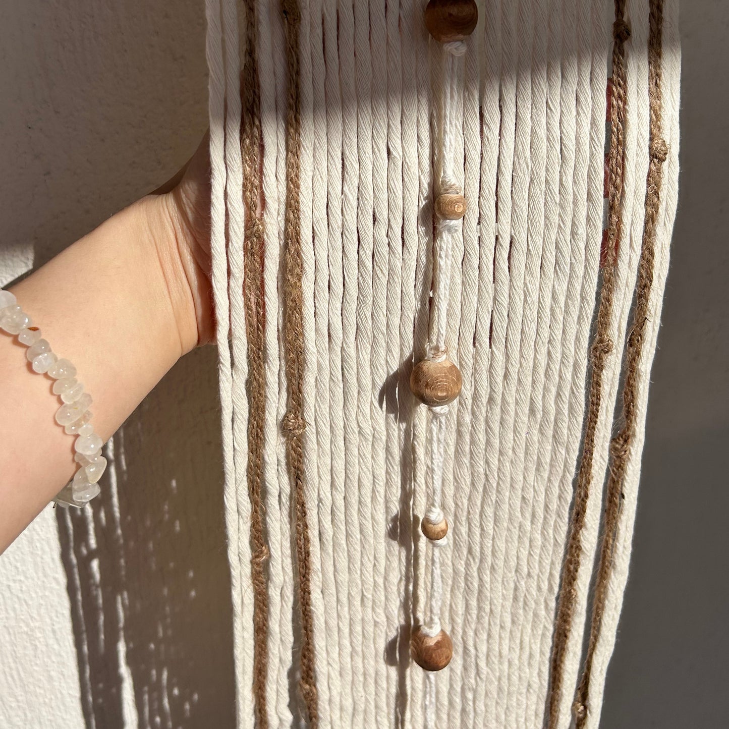 Handmade fiber wall art showing detailed knots and earthy-toned beadwork.